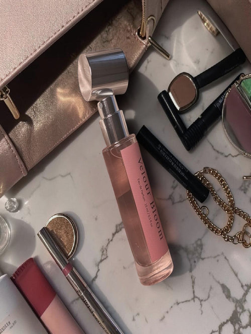 Velour Bloom mini perfume by LuxeScent Minis laying on marble countertop surrounded by makeup and accessories, luxury feminine fragrance, floral perfume for women